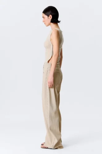 Pantalones holgados de talle bajo con tachuelas y corte acampanado – Beige